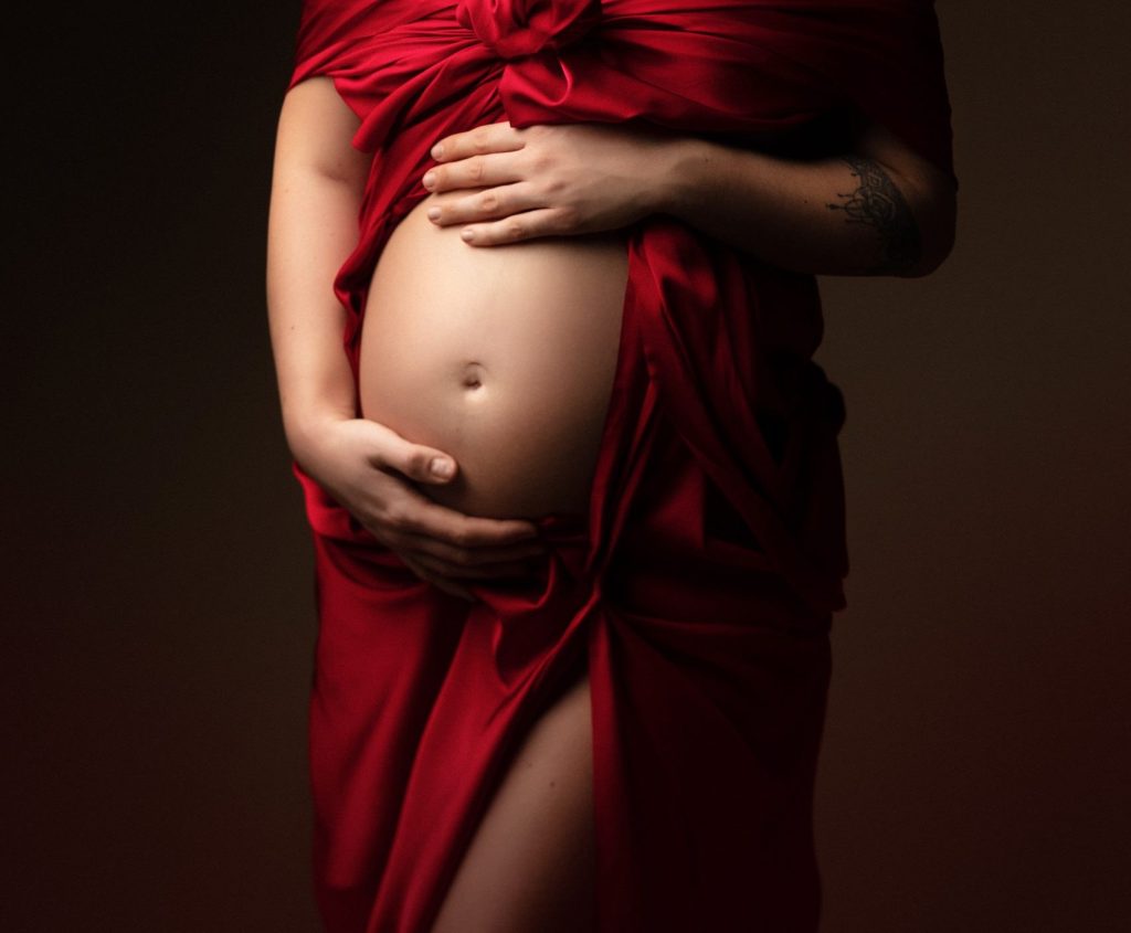 ventre arrondi d'une femme enceinte, mains posées dessus